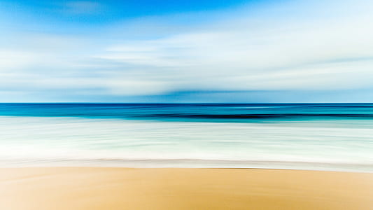 ocean with brown shoreline under white sky thumbnail