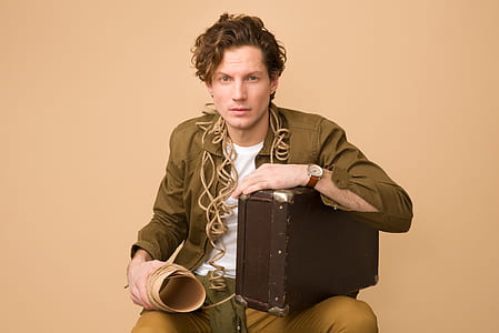 man sitting while holding suitcase thumbnail