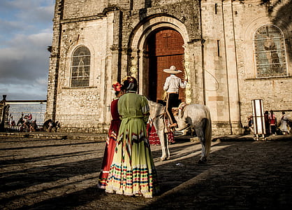 two women standing near person riding horse thumbnail
