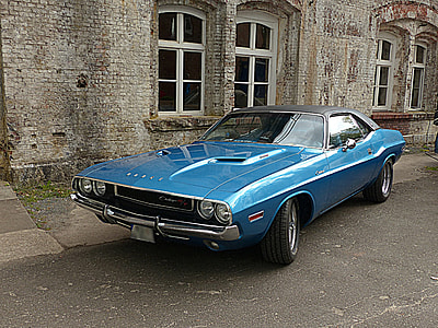 blue Dodge Challenger coupe parking near gray brick wall during daytime thumbnail