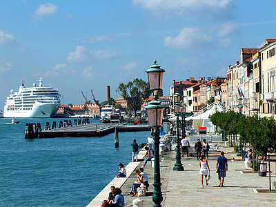 people walking and sitting on street near body of water during daytime thumbnail