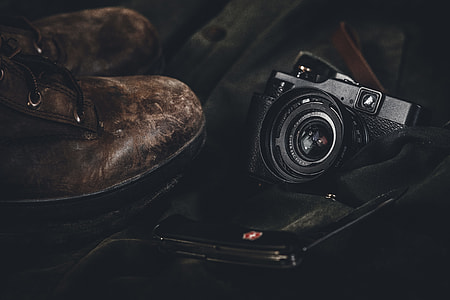 black point-and-shoot camera and pair of brown work bots thumbnail