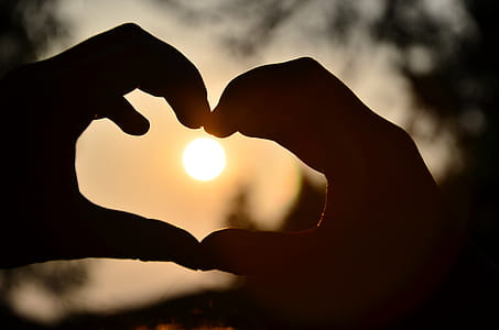 Silhouette of Person Hand Doing Heart Shape during Sunset thumbnail