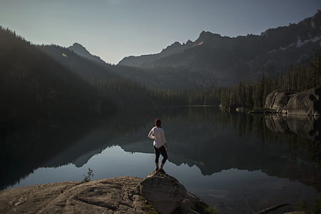 woman standing on rock facing body of water outdoor thumbnail