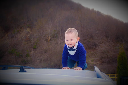 boy crawling on top of white vehicle at daytime thumbnail