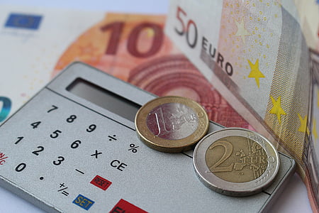 two 1 and 2 Euro coins on gray calculator thumbnail