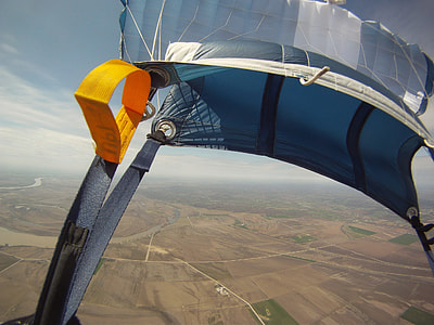 blue and white parachute above brown ground under blue and white clouds during daytime thumbnail