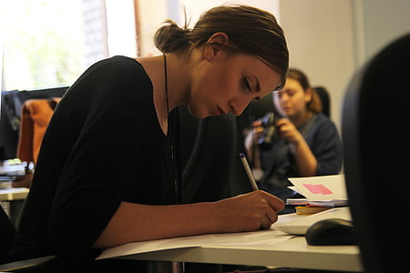 woman holding pen while writing thumbnail