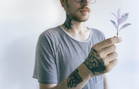 selective focus photography of man holding white leaves thumbnail