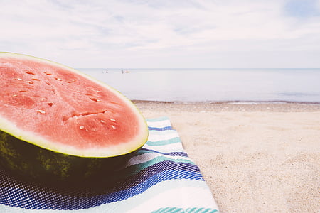 sliced watermelon on blue and white textile near seashore thumbnail