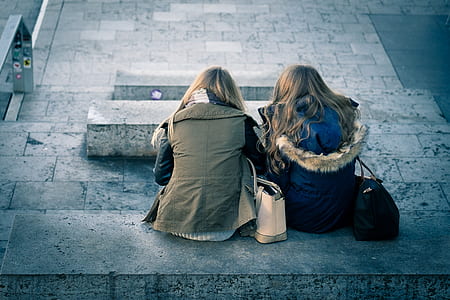 two women sitting on gray concrete bench thumbnail