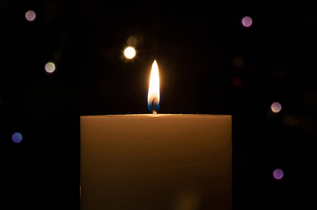 lighted candle with white orbs of light thumbnail