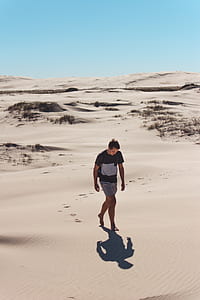 man walking on dessert under clear sky thumbnail