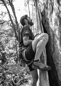 grayscale photography of man climbing tree thumbnail