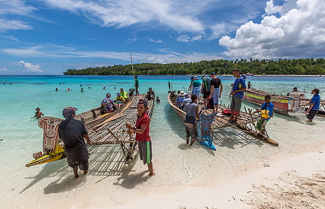 people standing near wooden boat on sea during daytime thumbnail