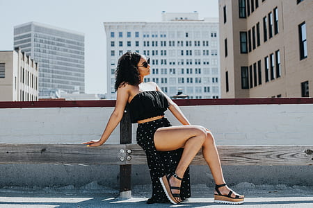 woman in black strapless top and skirt sitting on bench thumbnail