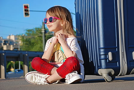 smiling girl sitting beside luggage bag thumbnail