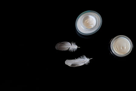 two white feathers beside candles thumbnail