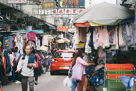 people at market with red Volkswagen Golf hatchback running on road at daytime thumbnail