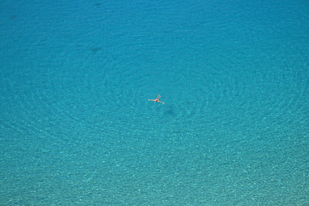 person swimming on body of water during daytime thumbnail