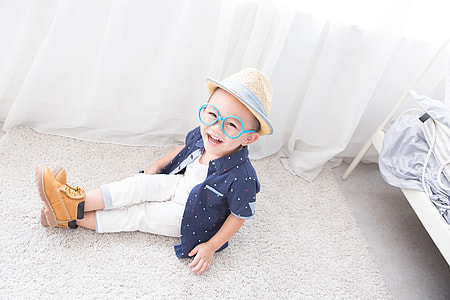 boy sitting on white area rug near white curtain thumbnail