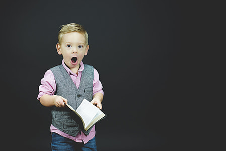 boy holding opened book while opening his mouth thumbnail