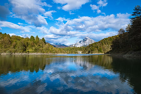 lake in the middle of trees and mountains thumbnail