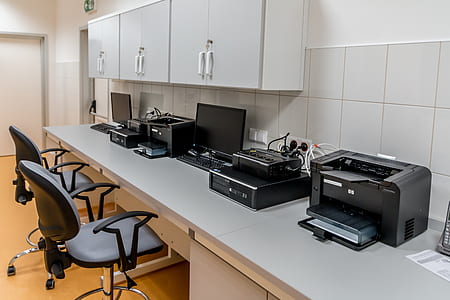 several black multifunction printers on wooden desk beside wall thumbnail