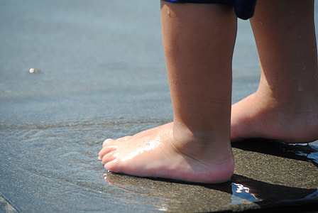 toddler's foot standing on body of water during day time thumbnail