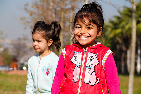 smiling girl in red hoodie standing outdoors next to girl in white jacket thumbnail