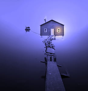 brown wooden house with wooden dock under purple sky thumbnail