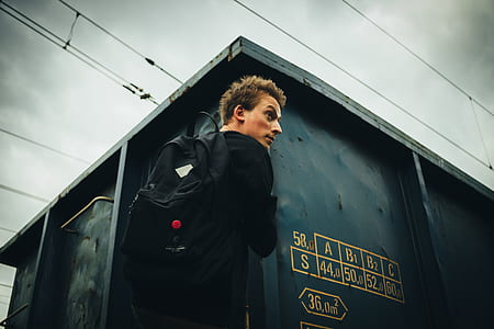 worm's-eye view of man carrying backpack in front of house thumbnail