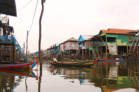 man riding on boat near houses during daytime thumbnail