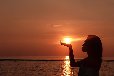 silhouette of woman raising right hand during sunset thumbnail