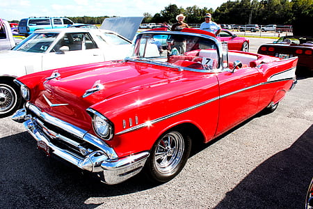 classic red and white Chevrolet Bel Air convertible coupe parked beside other vehicles at daytime thumbnail