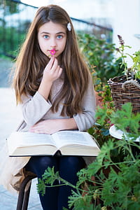 girl wearing white sweater with book opened on her lamp thumbnail