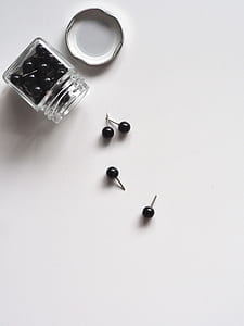 black head pins on white surface with jar thumbnail