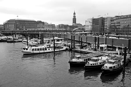 grayscale photography of boats on dock near buildings during daytime thumbnail