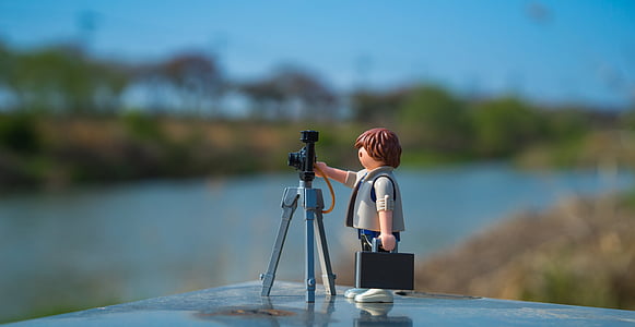 man holding camera figurine on black surface thumbnail