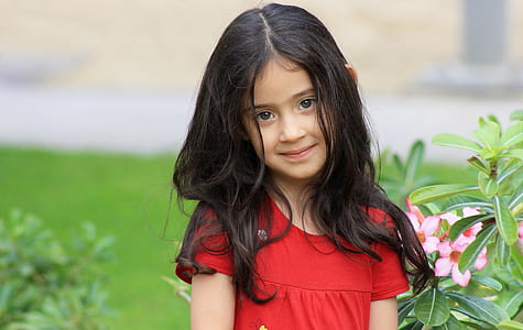 girl wearing red scoop-neck short-sleeved top near flower during daytime thumbnail