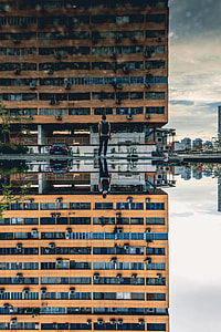 brown concrete building and standing man reflecting through water thumbnail