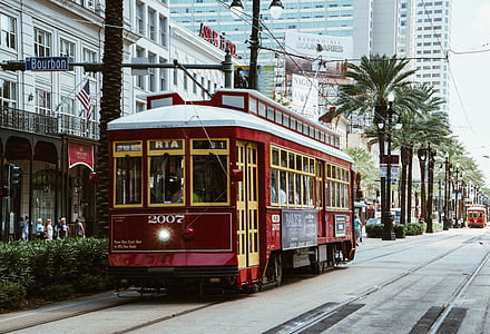 red train beside green trees and commercial establishments thumbnail