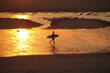 man holding surfboard near seashore during dawn thumbnail