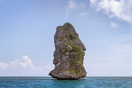rock formation on middle of body of water under cloudy sky thumbnail