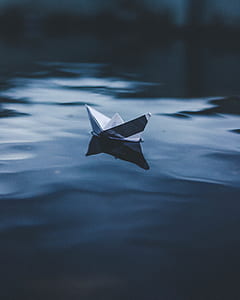 black and white paper boat on body of water thumbnail