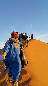 people walking with camel on dune desert thumbnail