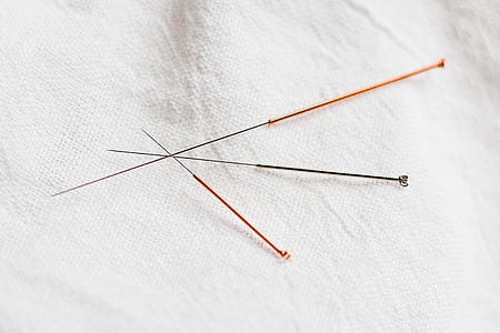 three assorted-color needles on white textile thumbnail