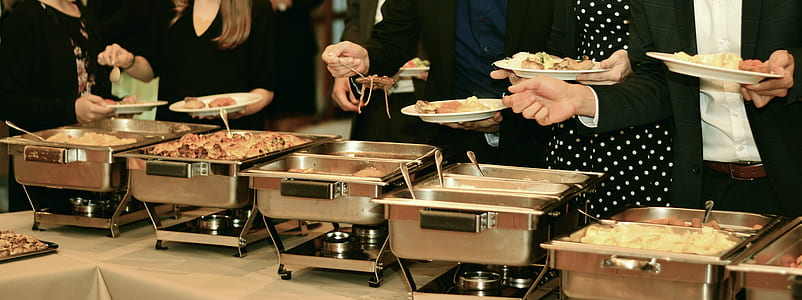 people standing next to table near chaffing dishews thumbnail