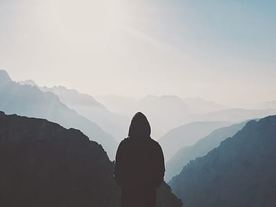 person standing on top of mountain under cloudy sky thumbnail