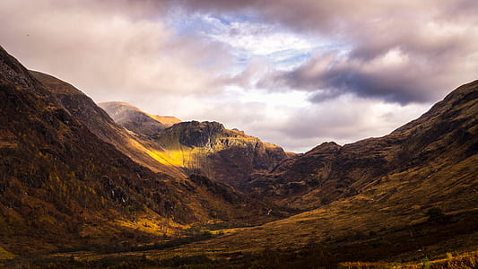 brown mountain under cloudy sky thumbnail